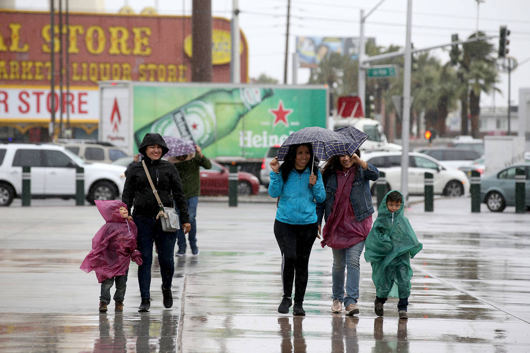 A family walks in wind and rain on Sahara Avenue at Las Vegas Boulevard in Las Vegas Tuesday, A ...