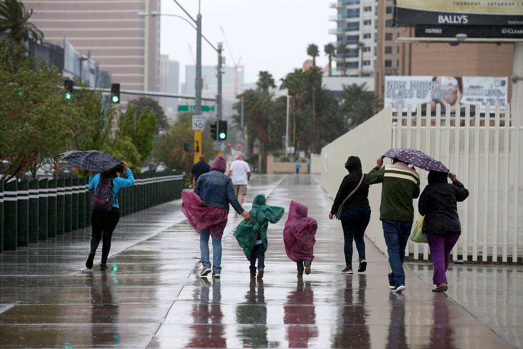 A family walks in wind and rain on Sahara Avenue at Las Vegas Boulevard in Las Vegas Tuesday, A ...