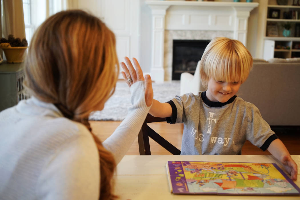 Kacey Ruegsegger Johnson high-fives with her son Corban as they finish a puzzle March 27, 2019, ...