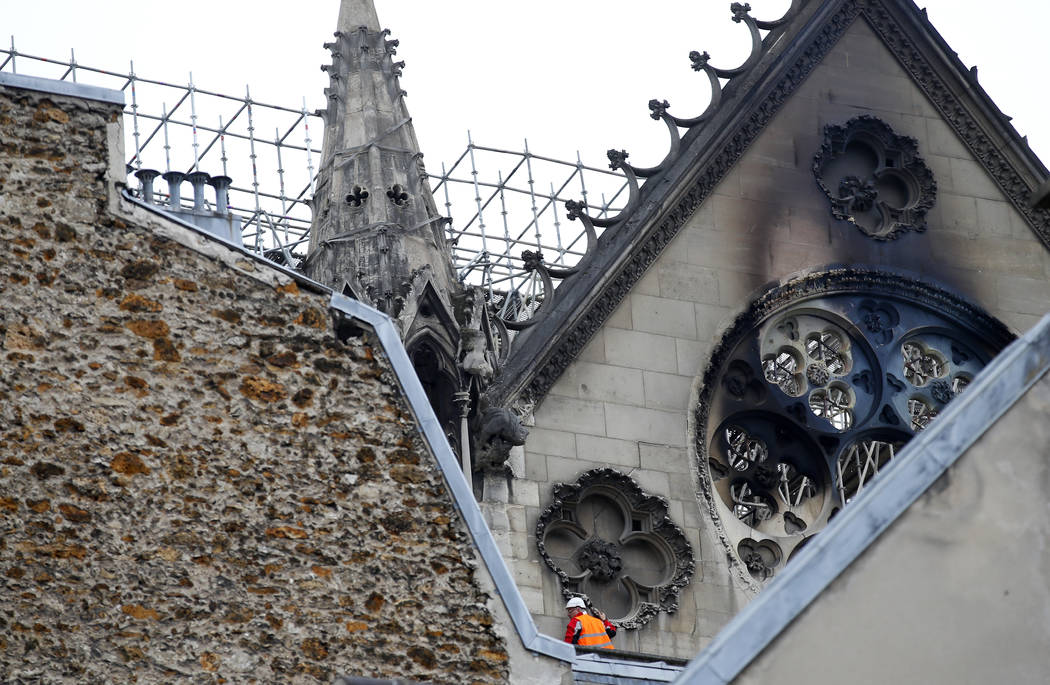 A man is pictured near chared glass windows Notre Dame cathedral Tuesday April 16, 2019 in Pari ...