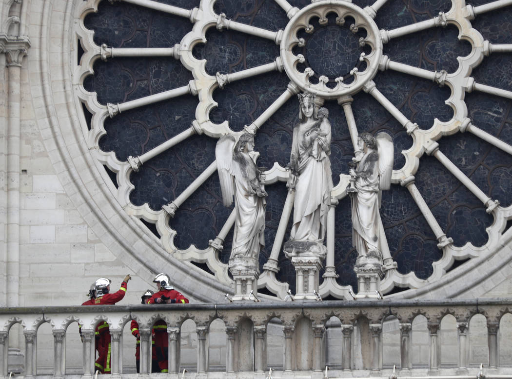 Firefighters talk near the rose window of Notre Dame cathedral Tuesday April 16, 2019 in Paris. ...