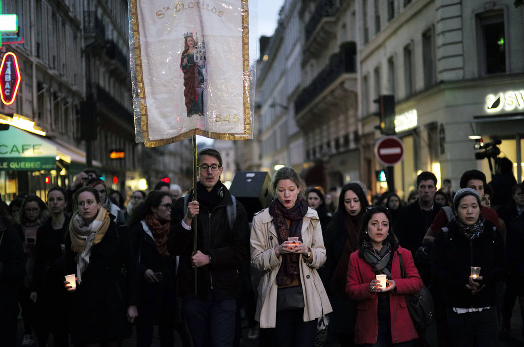 People walk toward the Notre Dame Cathedral to attend a vigil, in Paris, Tuesday April 16, 2019 ...