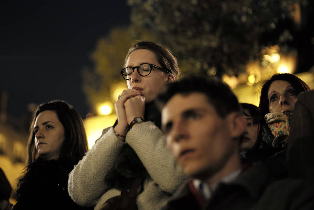 People attend a vigil in Paris, Tuesday April 16, 2019. Firefighters declared success Tuesday i ...