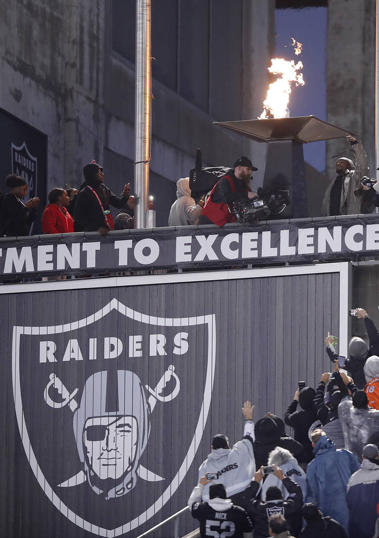 Oakland Raiders running back Marshawn Lynch, top right, lights a ceremonial torch for former te ...