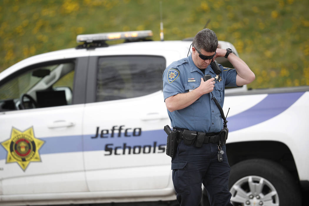 An officer from Jefferson County, Colo., Schools listens on his radio as students leave Columbi ...