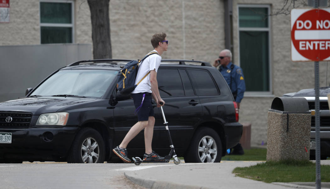 A student leaves by a scooter as parents wait in their vehicles for their children outside Colu ...