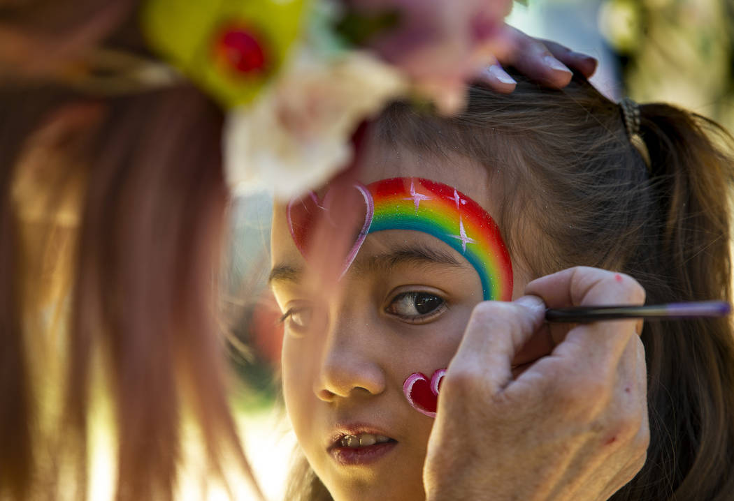 Alana Cano, 9, has a rainbow design painted on her face by Pamm Sundlie with Magic Wand Face Pa ...