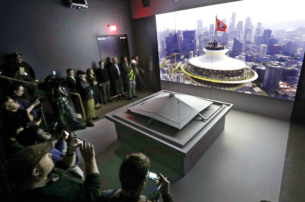 Media members stand near a model of the renovated KeyArena as a video about the plan plays behi ...