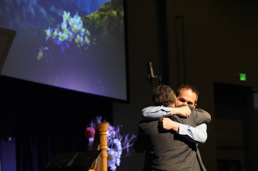 Tom Tonelli, facing camera, a teacher at Columbine High School, hugs former principal Frank DeA ...