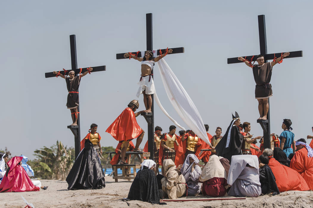 Ruben Enaje, center, dressed as Jesus, is seen nailed on cross for the 33rd year in a row durin ...