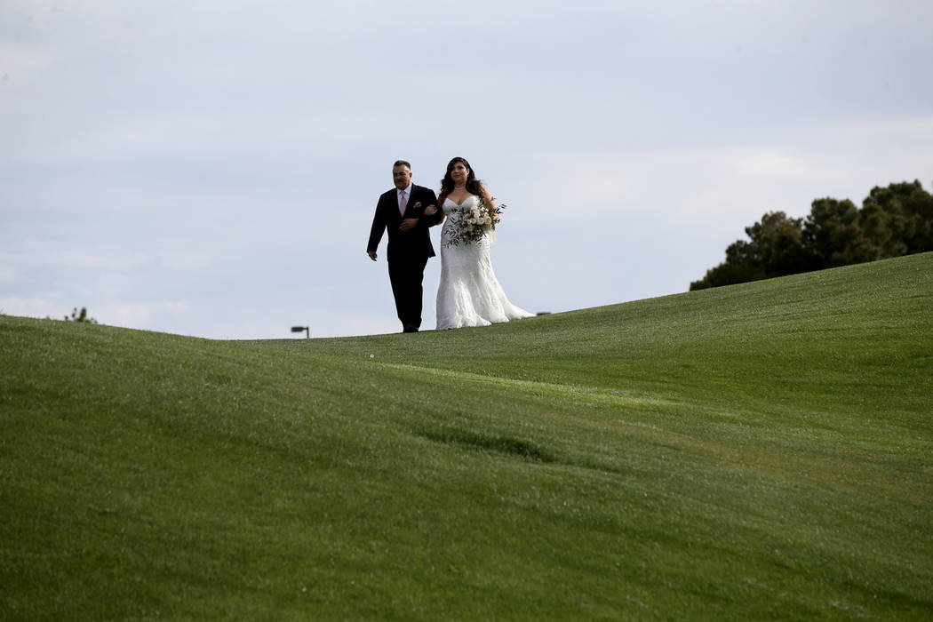 Kimberly King is walked down the isle by her father Manuel Flores at the Revere Golf Club in He ...