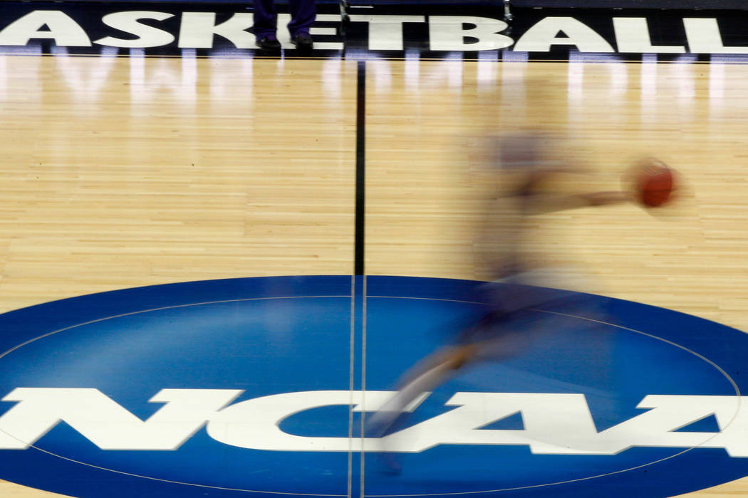 A player runs across the NCAA logo during practice at the NCAA tournament college basketball in ...