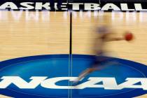 A player runs across the NCAA logo during practice at the NCAA tournament college basketball in ...