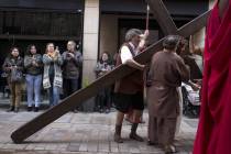 Visitors take pictures of a resident dressed as Jesus Christ during a Good Friday passion play ...