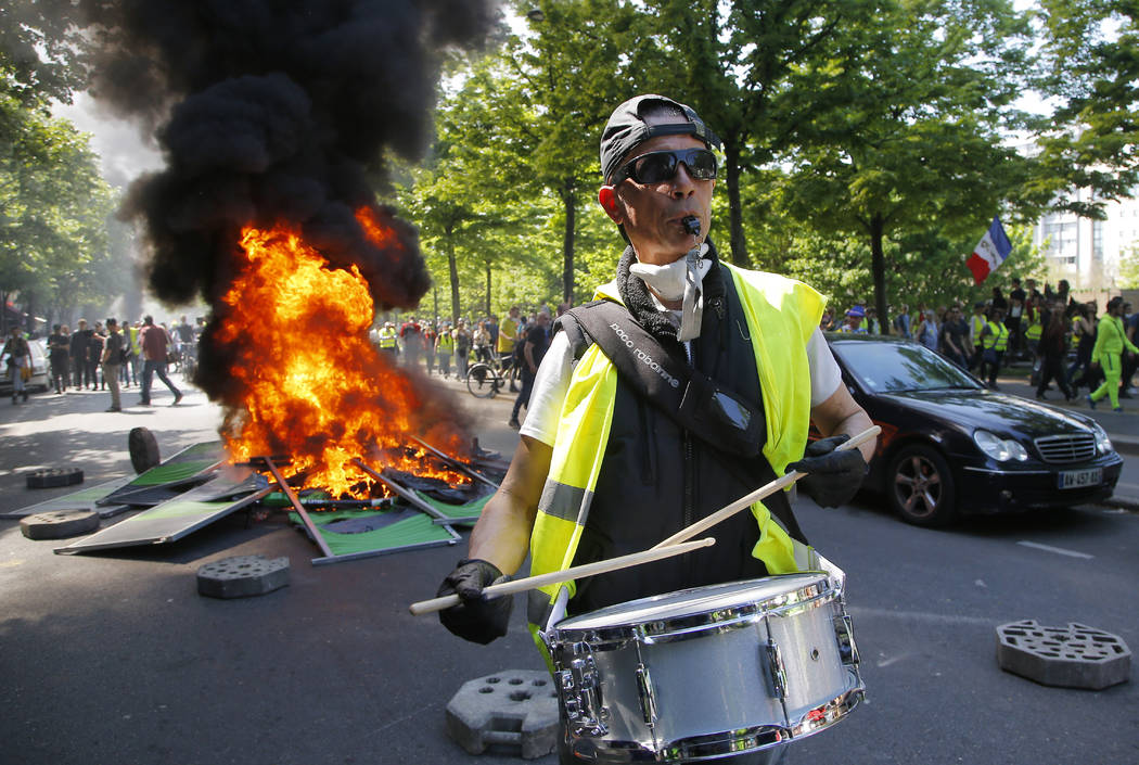 A man bangs a drum in front of a fire on the street during a yellow vest demonstration in Paris ...