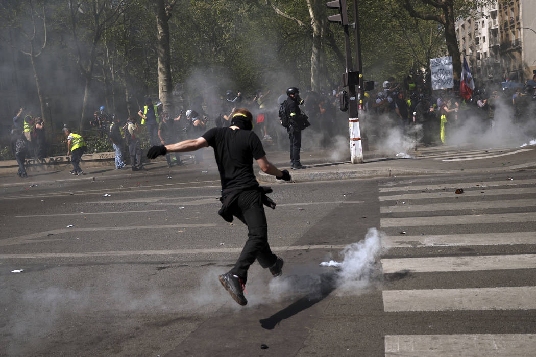 A protestor kicks back a tear gas canister during a yellow vest demonstration in Paris, Saturda ...