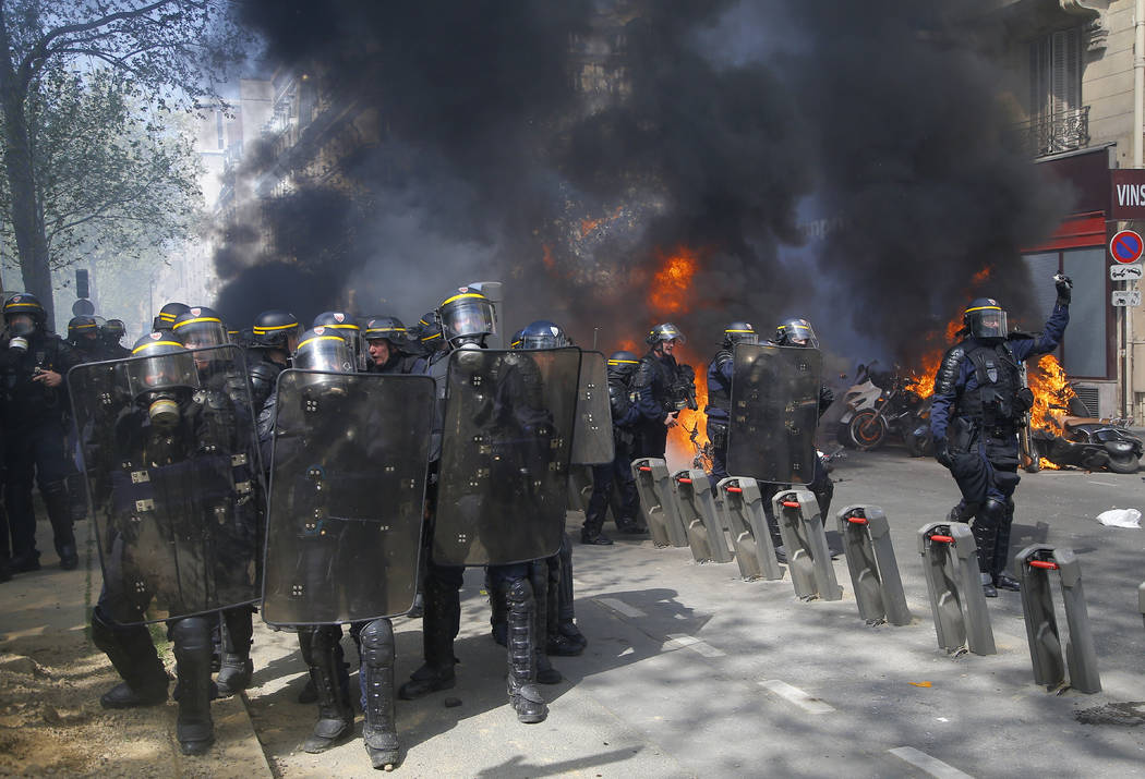 Police move in as motorbikes burn during a yellow vest demonstration in Paris, Saturday, April ...