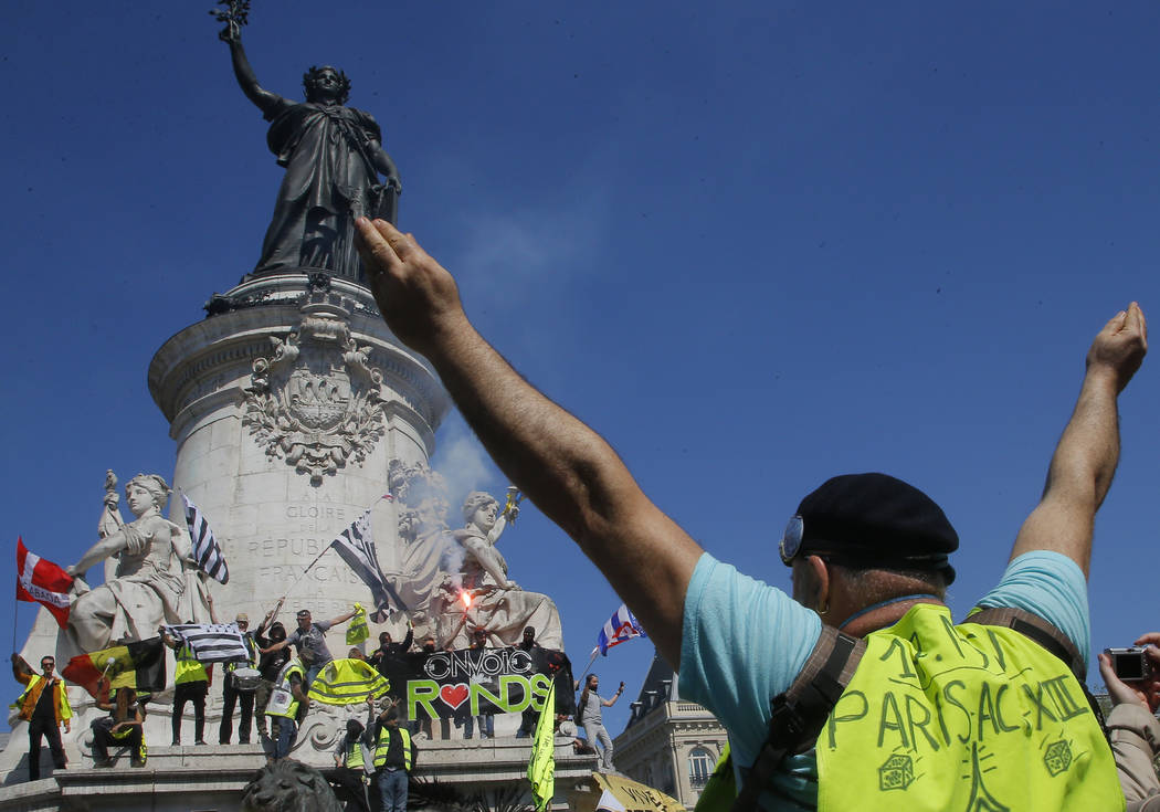 A protestor puts his arms in the air at the Place de Republique during a yellow vest demonstrat ...
