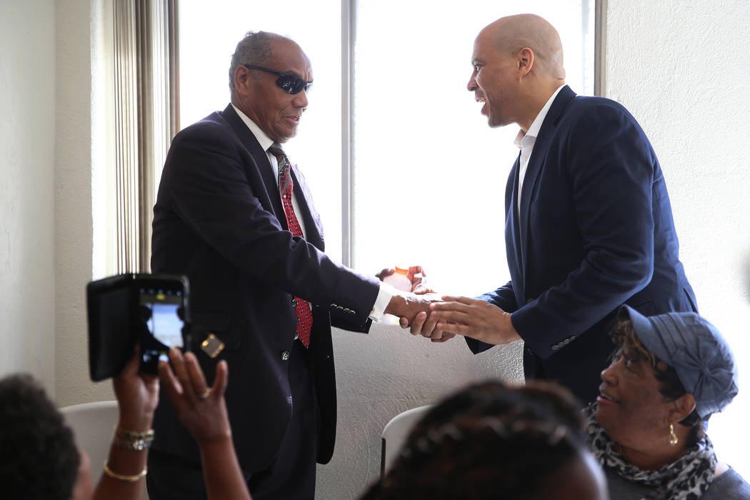 Democratic presidential candidate Sen. Cory Booker, D-N.J., right, shakes hands with the Rev. W ...