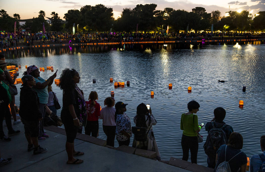 Lanterns float across the pond as people watch during the Water Lantern Festival at Sunset Park ...