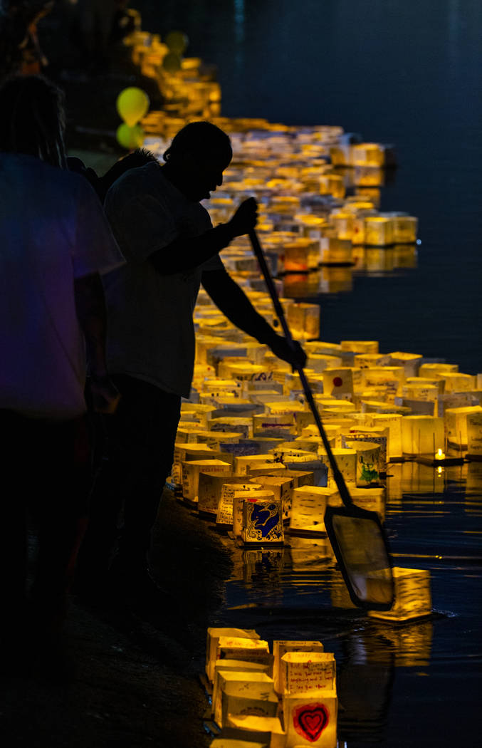 Lanterns are pushed into the lake as strong winds kept them near the shore during the Water Lan ...