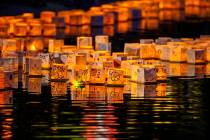 Lanterns gather near the lake edge as strong wings push them back during the Water Lantern Fest ...