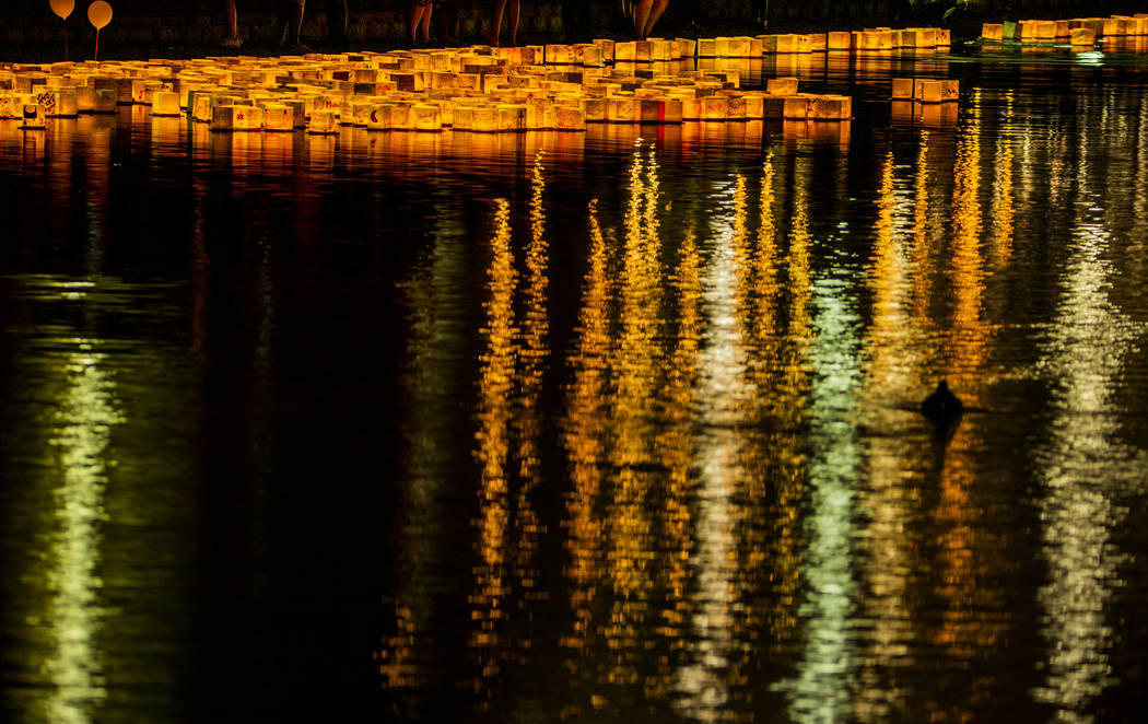 Lanterns gather near the lake edge as strong wings push them back during the Water Lantern Fest ...