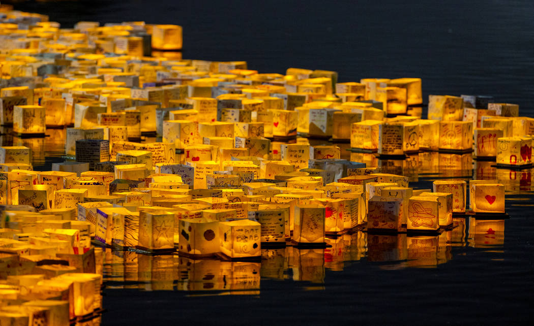 Lanterns gather near the lake edge as strong wings push them back during the Water Lantern Fest ...