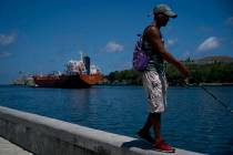 A fisherman walks on the Malecon seawall where an oil tanker can be see in the background in Ha ...