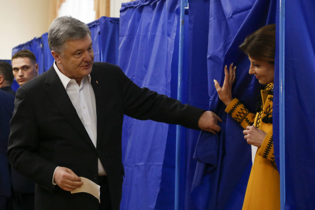 Ukrainian President Petro Poroshenko helps his wife Maryna to leave a booth at a polling statio ...