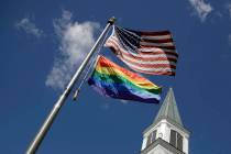 A gay pride rainbow flag flies along with the U.S. flag in front of the Asbury United Methodist ...