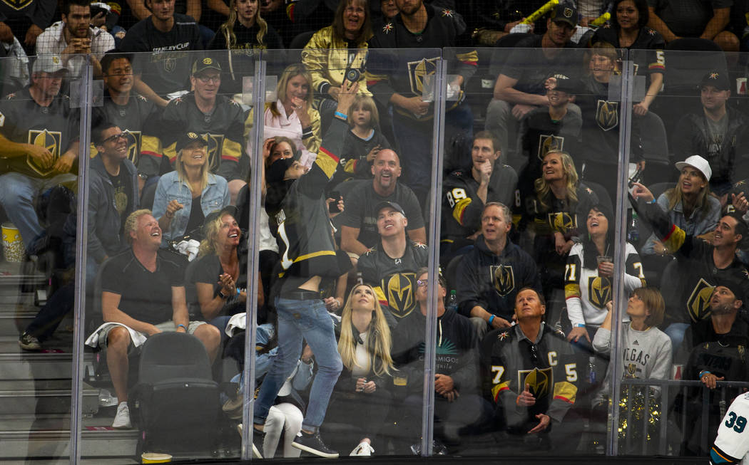 A fan reaches up for a puck that goes over the glass during the second overtime period of Game ...