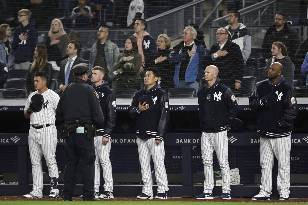 New York Yankees players listen to "God Bless America" during the seventh-inning stre ...