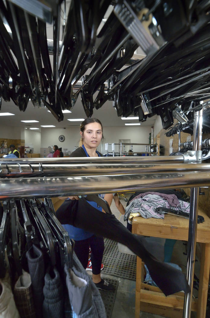 Merchandise processor Kassandra Van Duyne hangs sorted clothes in the warehouse at the Goodwill ...