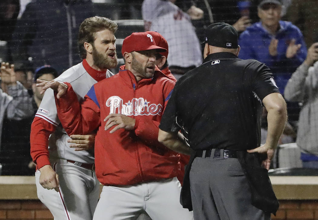 Philadelphia Phillies manager Gabe Kapler, center, restrains Bryce Harper, left, while arguing ...