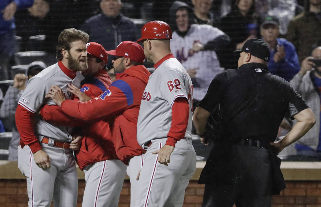 Philadelphia Phillies' Bryce Harper, left, is restrained while arguing with umpire Mark Carlson ...