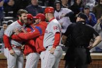 Philadelphia Phillies' Bryce Harper, left, is restrained while arguing with umpire Mark Carlson ...