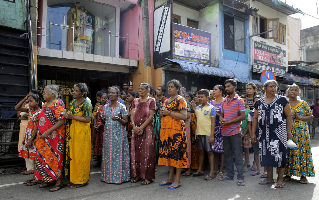 Sri Lankans pray during a three minute nationwide silence observe to pay homage to the victims ...
