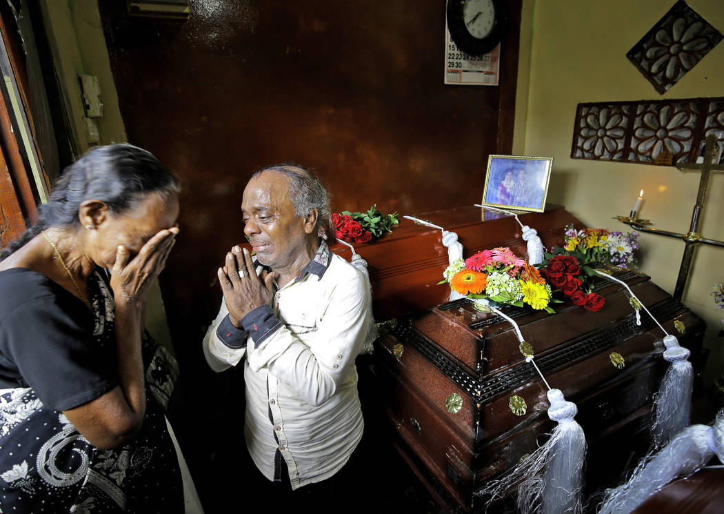 A Sri Lankan family mourns next to the coffins of their three family member, all victims of Eas ...