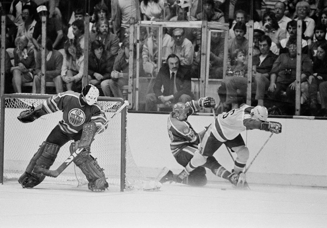 Edmonton Oilers' goal tender Grant Fuhr watches teammate Jari Kurri (17), center in dark unifor ...