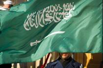 FILE - In this March 22, 2018 file photo, an Honor Guard member is covered by the flag of Saudi ...