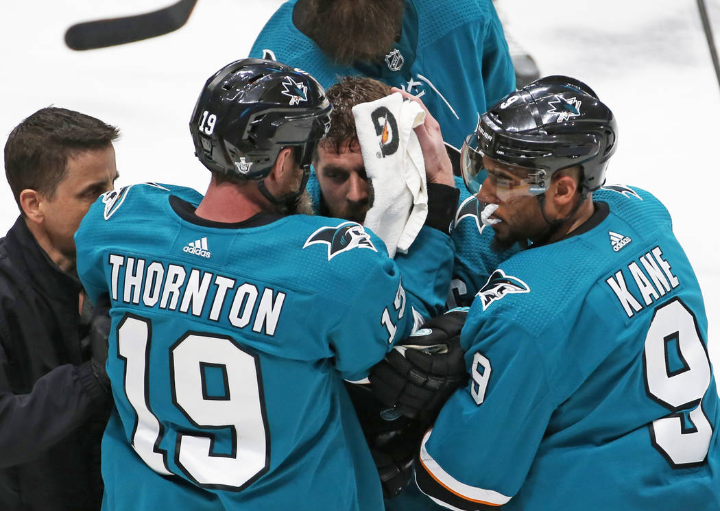 Sharks center Joe Pavelski, middle, is helped off the ice by Sharks left wing Evander Kane and ...