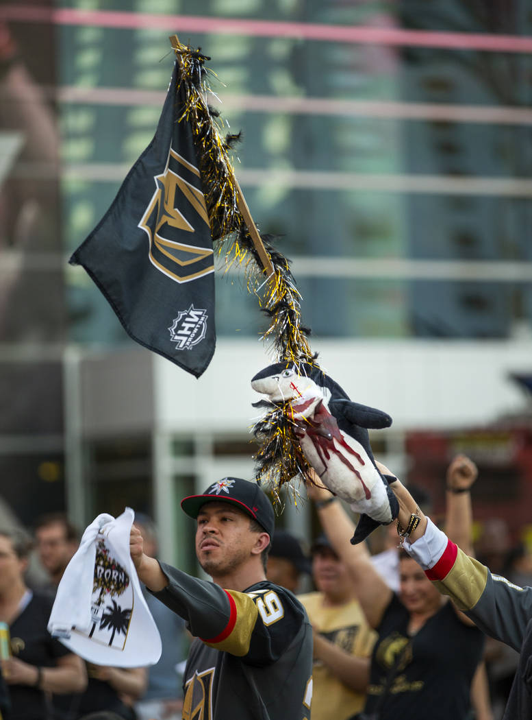 A Golden Knights fan flies a flag with bloody shark attached while celebrating a goal with othe ...