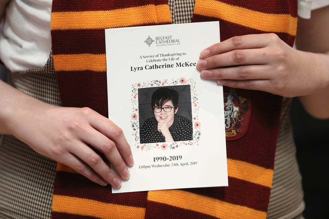 A mourner wearing a Harry Potter Gryffindor House scarf holds an order of service as she arriv ...
