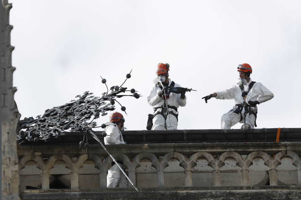 Workers stand on a roof of Notre Dame cathedral Wednesday, April 24, 2019 in Paris. Professiona ...
