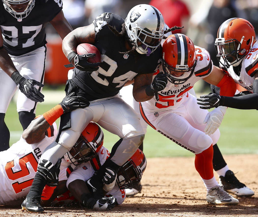 Oakland Raiders running back Marshawn Lynch (24) is stopped by Cleveland Browns outside linebac ...