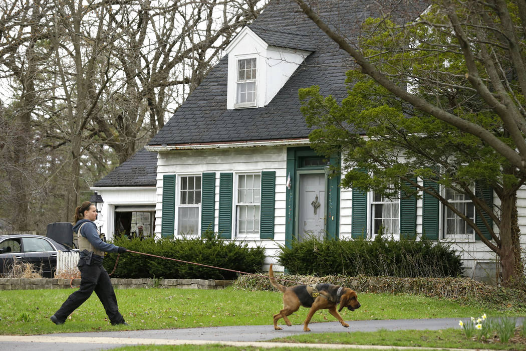A blood hound K-9 officer and his handler sniffs the ground in front of the home of 5-year-old ...