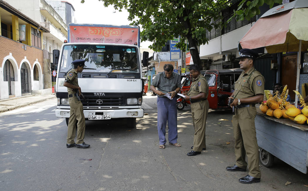 Sri Lankan police officers perform security checks on a truck at a roadside in Colombo, Sri Lan ...