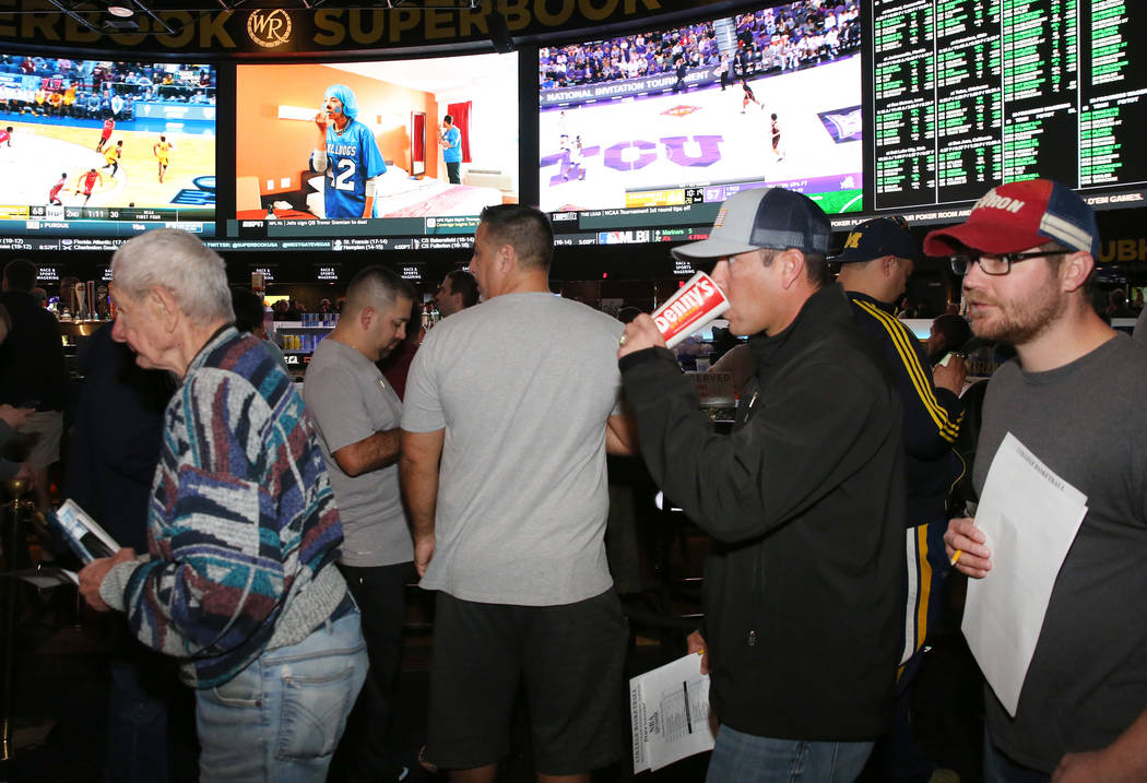 Fans lined up to place their bets during the first day of the NCAA basketball tournament at the ...