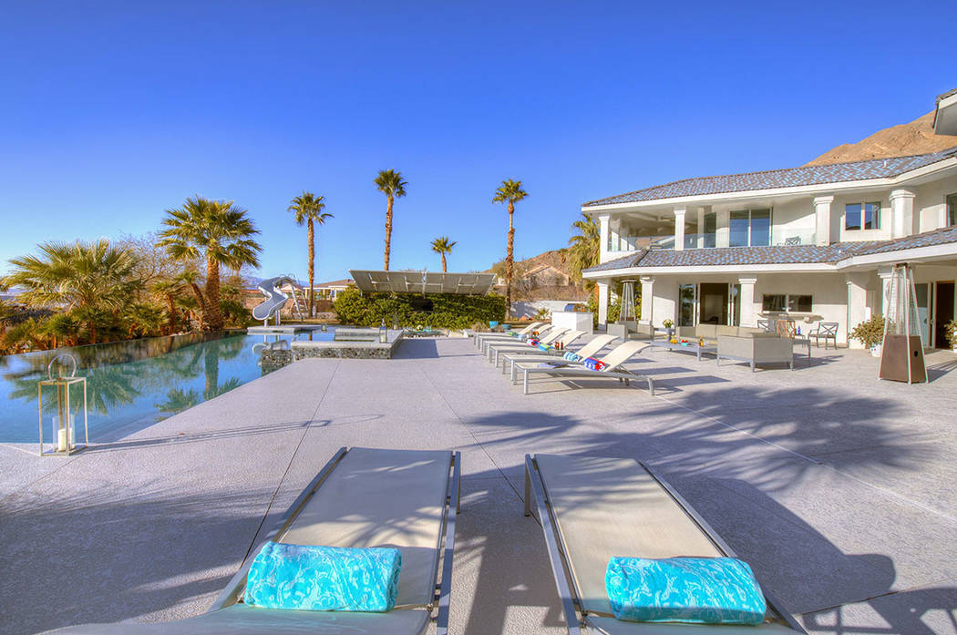 The pool area has a water slide and mature palm trees. (Sotherby’s International Realty, Synergy)